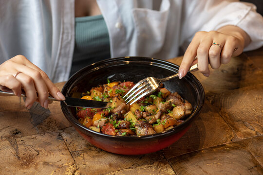 woman eating fried meat with vegetables in a ceramic bowl on a light background. Selective focus.