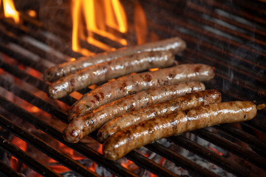 Grilling sausages on the grill with flames and smoke.