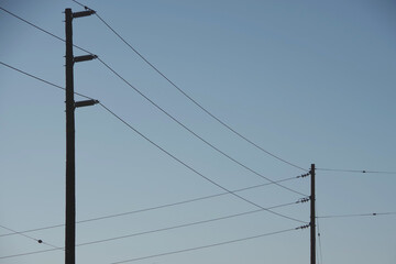 Electricity distribution pylons and power lines under blue sky
