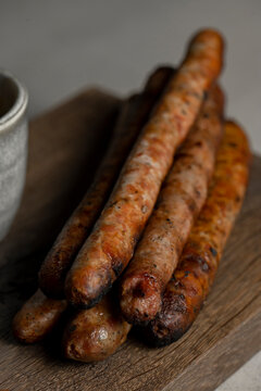 Grilled sausages with mustard and herbs on a wooden board