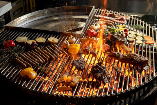roasted meat and vegetables on the grill with flames and vegetables, close up