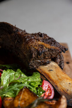 roasted veal rib with baked potatoes and vegetables on a wooden board