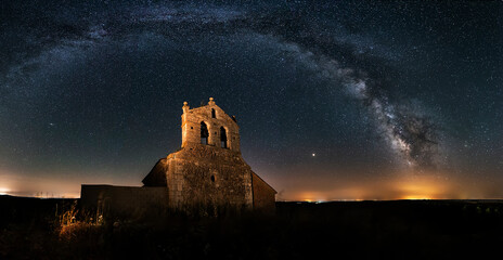 Night view of the Romanesque church of Dehesa de Romanos in Palencia with the starry sky and the arch of the Milky Way framing the hermitage