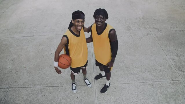 View from above of portrait of two African American sportsmen posing for camera together on outdoor playground after game
