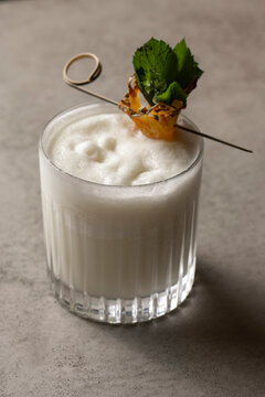 Pina colada cocktail with pineapple and mint on a gray background