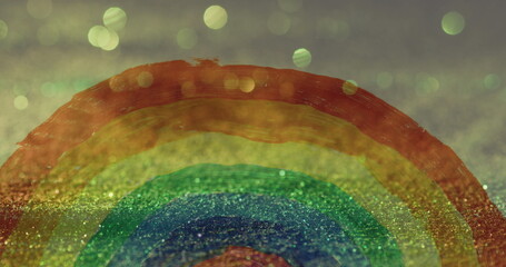 Image of hand painted rainbow over glowing sand falling in background