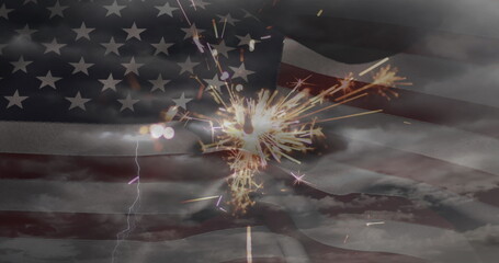 Fototapeta premium Image of glowing sparkler and clouds on sky over american flag