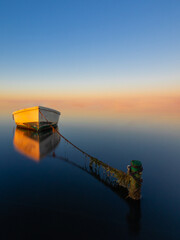 Boat anchored on the beach at sunset with an infinite sky.