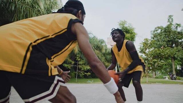 Low angle of black male basketball players training on streetball outdoor playground before matchLow angle of black male basketball players training on streetball outdoor playground before match
