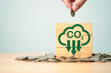 Hand putting coin with carbon reduction icon on heap of coins for carbon dioxide absorption to carbon credit footprint can make money ,limit global warming from climate change concept.