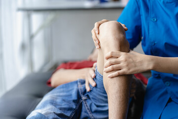 Physical therapy concept Treat a male patient's injured knee in the clinic. Holding hands of a...
