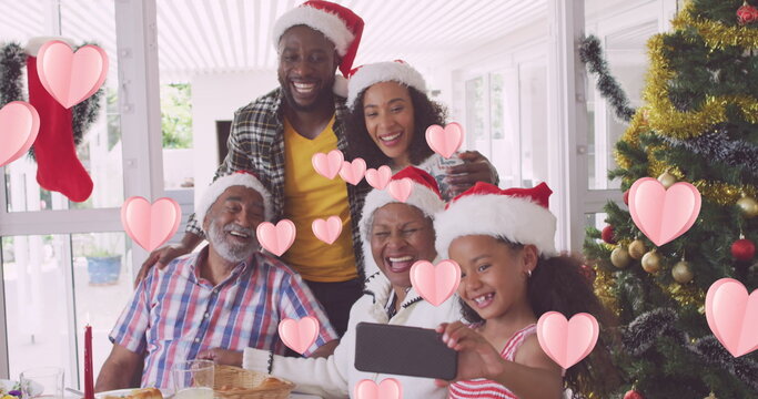 Image of heart icons over african american family with santa hats