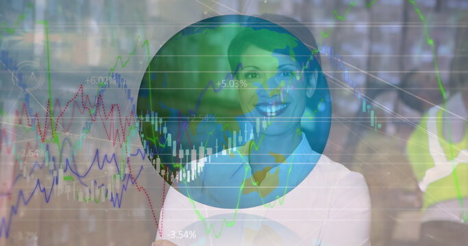 Image of financial graphs and globe over happy biracial female warehouse worker