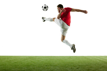Motivated and competitive male football player hitting ball in jump, during training session of stadium isolated on white background. Concept of professional sport, game, competition, tournament