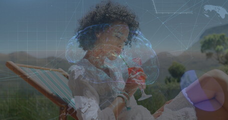Image of brain, globes and data processing over biracial woman drinking cocktail on beach