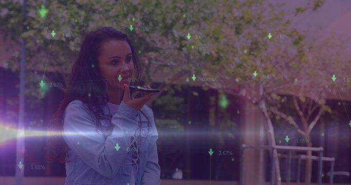 Image of green arrows and data processing over smiling biracial woman using smartphone outdoors - Powered by Adobe