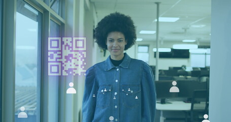Image of gr code and icons over biracial woman smiling in office - obrazy, fototapety, plakaty