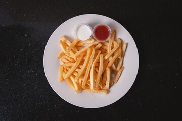 Overhead view of French fries with toppings served on a white plate.