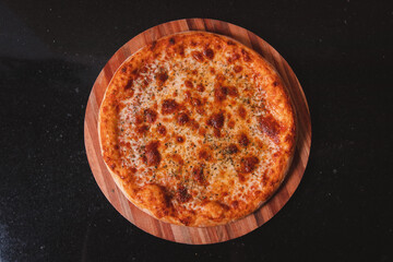 Overhead view of a mozzarella pizza on a black table.
