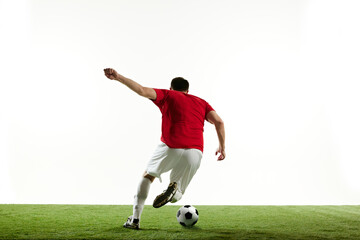 Man, football player in motion during game training, running on filed with ball isolated on white background. Concept of professional sport, game, competition, tournament, action. Back view - obrazy, fototapety, plakaty