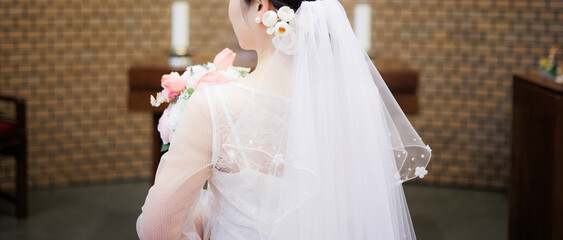 Bride appearance from behind wearing a beautiful white dress in Catholic Church. It is a happy...