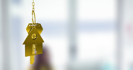 Image of gold house key fob and key dangling over out of focus interiors with copy space