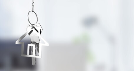 Image of silver house key fob and key dangling over out of focus interiors with copy space