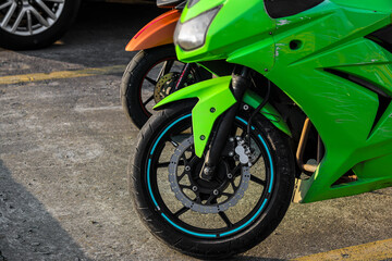 Fototapeta na wymiar sport green bike parked. parking background. sports motorcycle with aluminum frame. shock absorber fork and brake disc on the front wheel