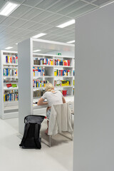 A modern library in Germany. A girl is reading books in the library.