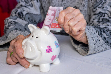 Sweden money, Pensioner puts 500 Swedish kronor into a piggy bank, financial concept, Saving and financial security of elderly people