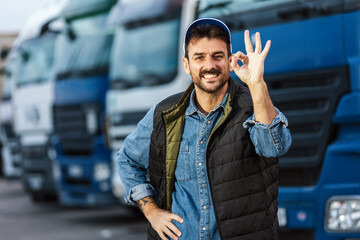 Happy confident male driver standing in front of his truck.