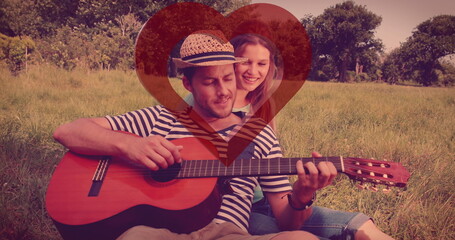 Image of red heart over couple in love with guitar - obrazy, fototapety, plakaty
