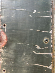 A rusted metal surface with holes and paint splatters