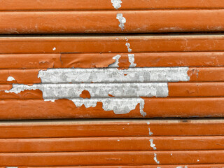 A shutter with a large paint got removed, and the surrounding area is covered in rust