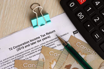 Canadian T2 tax form Corporation income tax return lies on table with canadian money bills close...