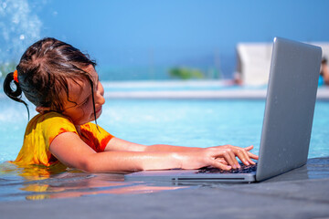 Learning and study everywhere and always. Portrait of young girl learning with laptop computer in the swimming pool.  Horizontal image.