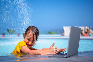 Conceptual image of distance learning. Portrait of young beautiful happy girl learning with laptop computer in the swimming pool. Selective focus on eyes.