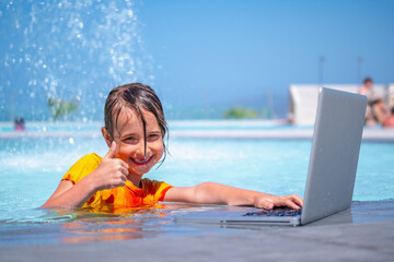 Distance learning. Portrait of young happy girl learning with laptop computer in the swimming pool. Horizontal image.