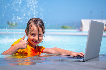 Distance Learning, learning and study everywhere and always. Young girl learning with laptop computer in the swimming pool. Horizontal image.