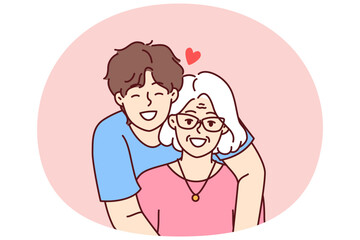 Noble guy teenager hugging elderly grandmother showing love and care for ancestors and communicating with family. Happy retired woman near caring son spending time in family atmosphere - 785546508