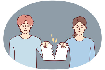 Angry man and woman holding sheet tearing joint paper after quarrel or family disagreement. Guy and girl with hatred in their eyes tear document confirming marriage - 785546903