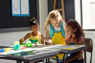 Fototapeta premium In school, three young girls are focusing on painting in art class