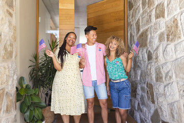 Group of friends, one Asian male and two biracial females, holding American flags