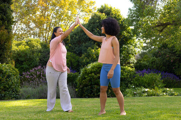 Biracial mother and daughter are high-fiving in garden at home