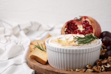 Board with tasty baked camembert, croutons, walnuts and pomegranate on table, closeup. Space for...
