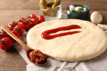 Pizza dough and products on wooden table, closeup
