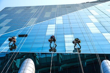 Group of high rise workers hanging on access rope cleaning highrise glass building in Seoul, South Korea © Jack Tamrong