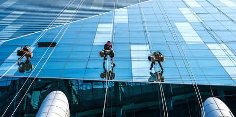 Group of high rise workers hanging on access rope cleaning highrise glass building in Seoul, South...