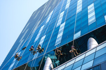 Group of high rise workers hanging on access rope cleaning highrise glass building in Seoul, South Korea © Jack Tamrong