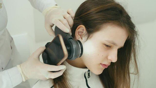The doctor applies a special magnifying glass to the hair growth zone. She rearranges it on her cheek and an enlarged image of the birthmark is visible on the screen. High quality 4k footage